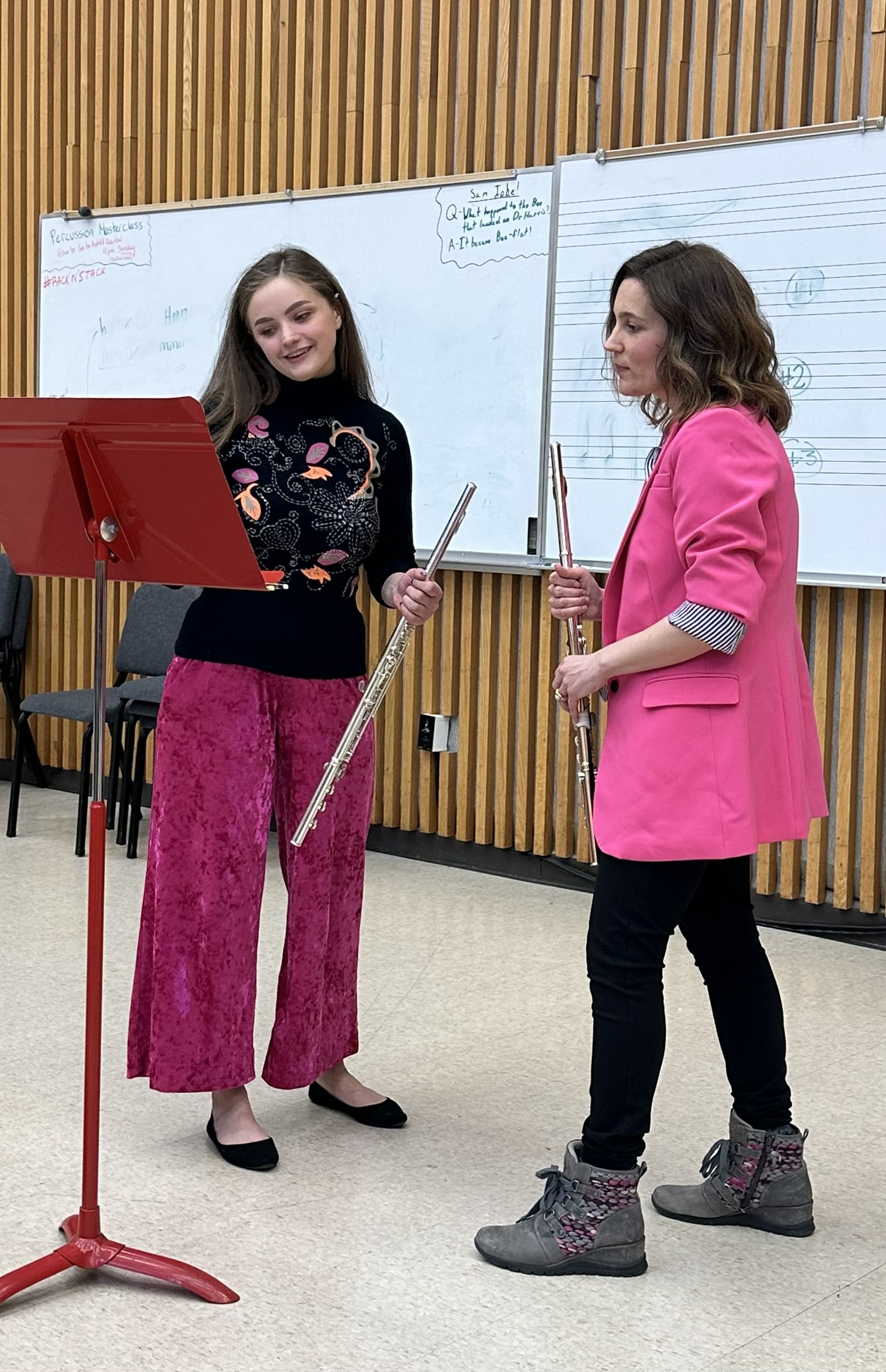 Abigail Walsh working individually with a flute student at a music stand.